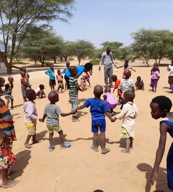 young children outdoors holding hands in a circle formation