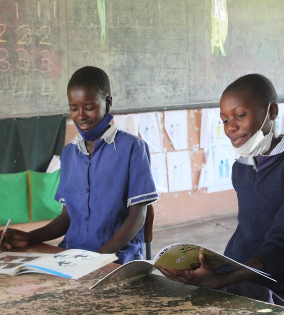 Two children from Zambia learning and reading in their classroom.