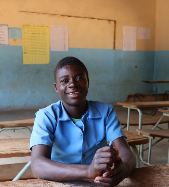 young man in class posing for a photo at a desk