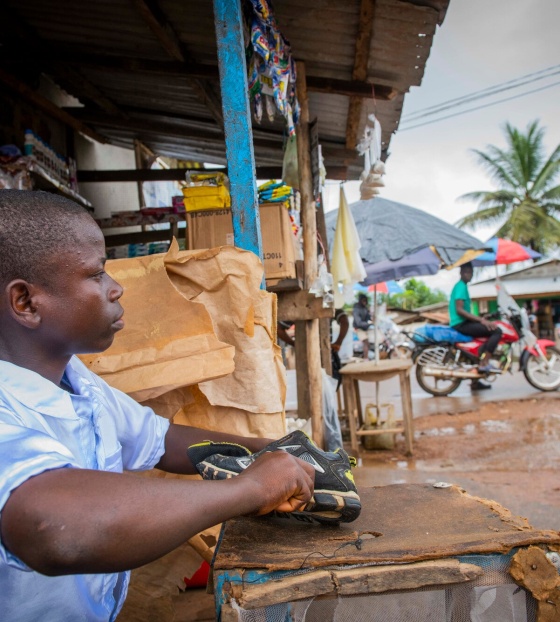 Momo, a child from Liberia working to repair shoes to earn extra money for him and his family.