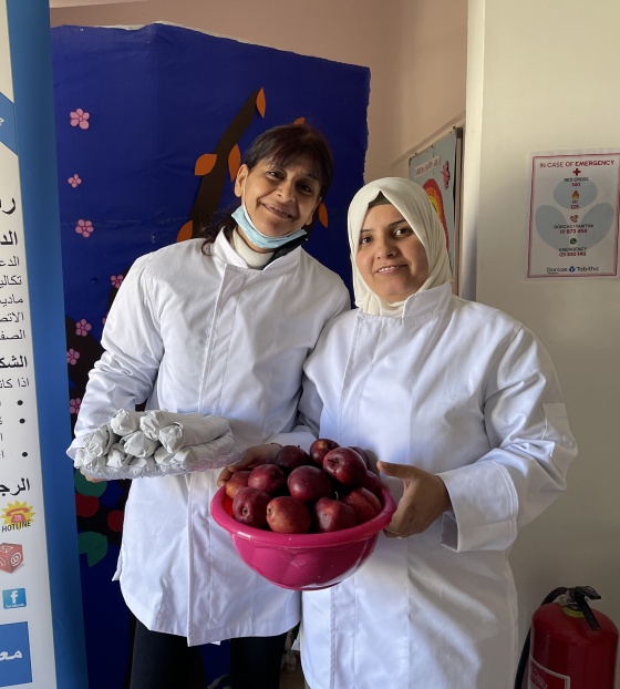 Two female volunteers holding bowls of food and posing for a photo