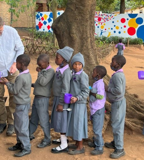 line of children waiting to receive servings of food outdoors