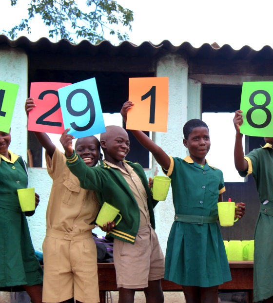 a group of schoolchildren each holding up signs that make up the number '2429182'
