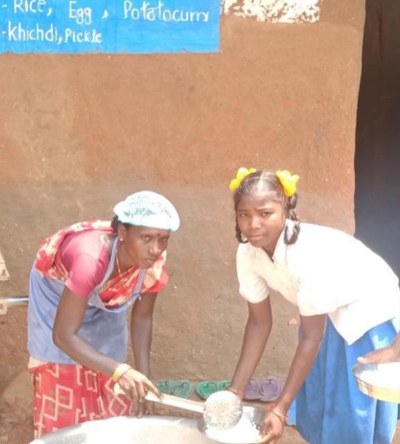Arushi with a friend, receiving their meal from a volunteer.