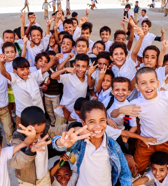 Large group of children smiling and looking into camera.