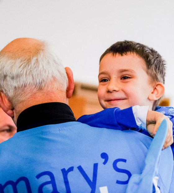 A volunteer carries his grandson at a fundraising event