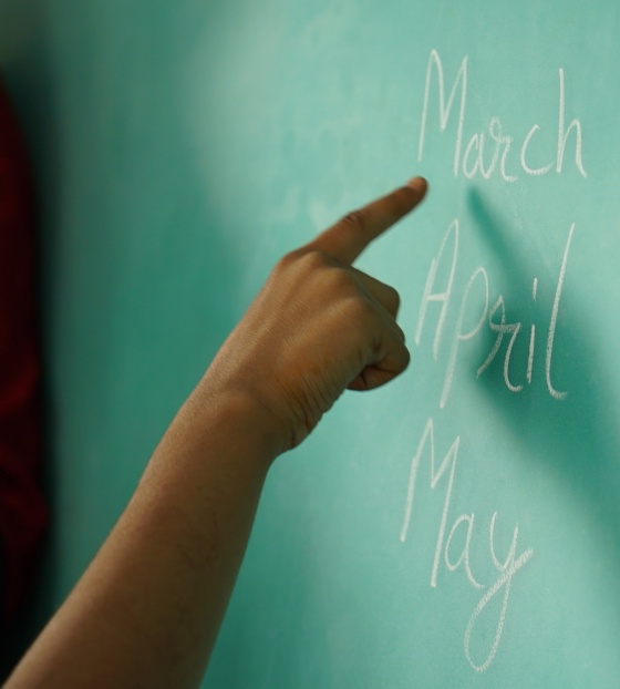 A finger points at a blackboard