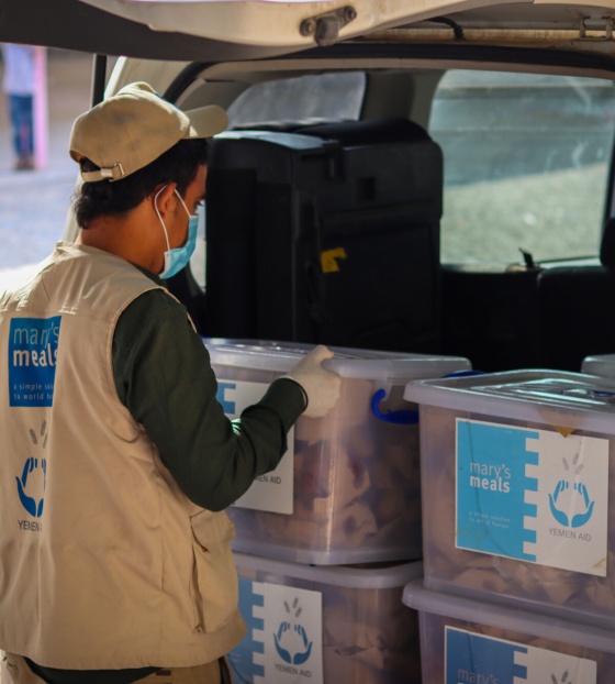 a volunteer loads a car with supplies in Yemen