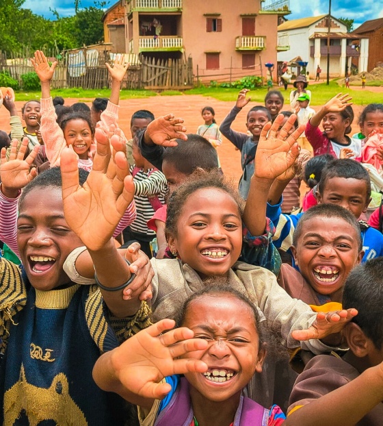 Large group of children smiling and looking into camera.