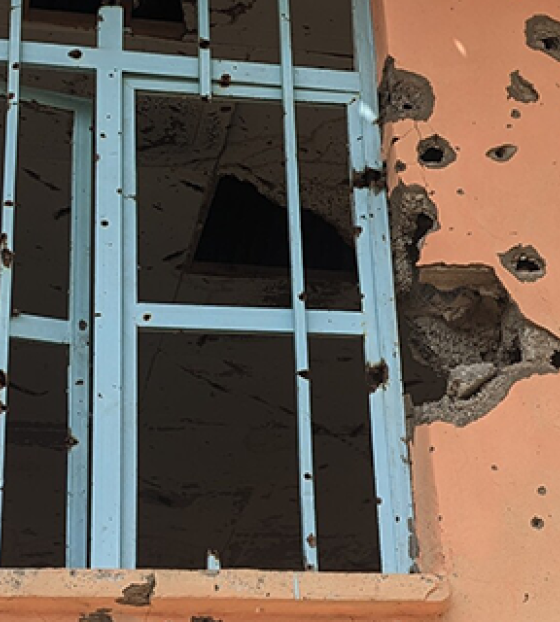 Image of school windows with bullet holes strewn across the outside wall.