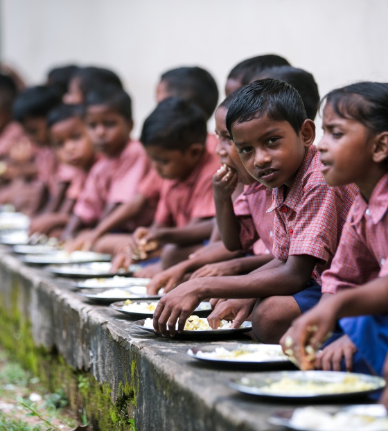 a group of young Indian children sitting in a line