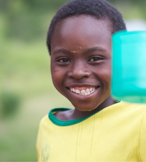 A young boy raises his mug of porridge