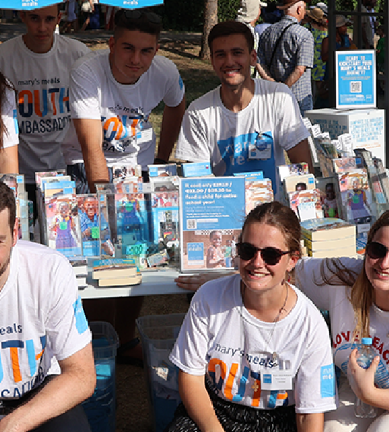 Image of young Mary's Meals supporters and volunteers manning a stall for Mary's Meals.