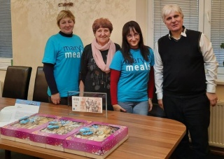 four people posing for a photo in front of a table laden with baked goods