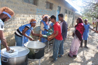 a queue of displaced peoples collecting food from an aid station