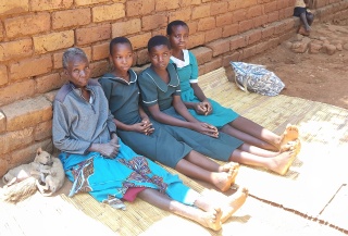 four women leaning against a wall whilst sat on the ground