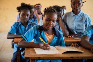 A child from Zambia writing in her jotter while learning in class.