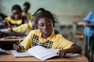 A young girl from Zimbabwe sitting at her desk in a classroom learning.