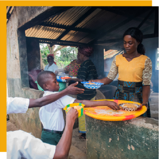 volunteer serving food to small children from a kitchen window