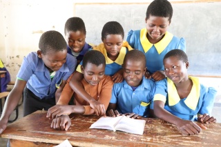 Ulemu with his classmates reading a book. 