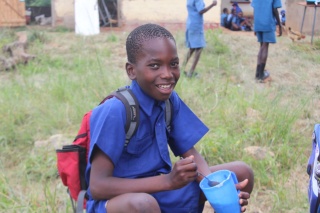 A child from Zambia enjoying Mary's Meals in their place of learning.