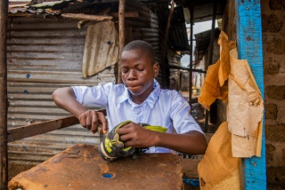 Momo working to repair shoes to support his family. 