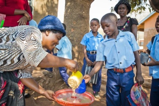 A child being served Mary's Meals by a volunteer. 
