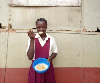 Jamkai, a school pupil from Kenya enjoys a bowl of Mary's Meals at school.