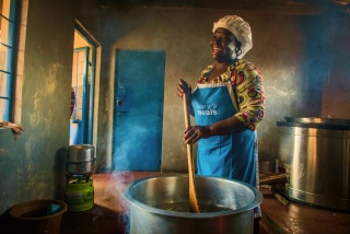 A volunteer cook laughs as she prepares food