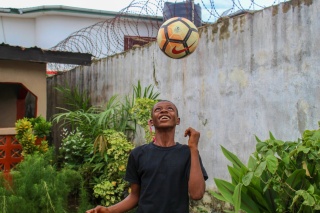 A boy keeps a football up in the air
