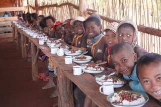 Children enjoying a meal at school and smiling into camera. 