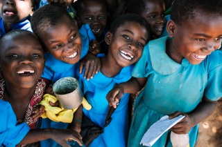 Children receiving a meal, smiling and laughing together. 