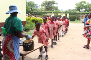 Children in Zambia waiting in line for the school meal from a Mary's Meals Volunteer.