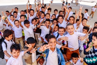Large group of children smiling and looking into camera.
