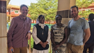 Partners, Volunteers and staff smiling into camera while visiting a school.