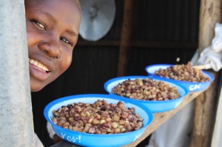 A volunteer cook pokes her head out of the kitchen as three plates of food sit, waiting to be collected.