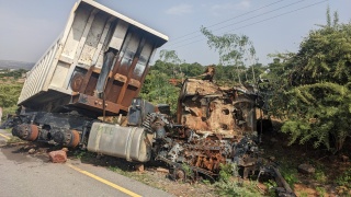 Image of a large truck that has been attacked left destroyed and rusting by the roadside.