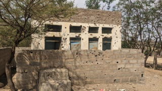 Image of a building with bullet holes strewn on the walls.