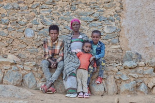 Letemariam and her grandchildren sitting outside their home looking into the camera.