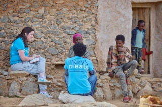 Mary's Meals workers and volunteers sitting with Letemariam and her grandson.