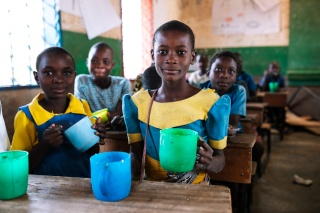 Children enjoying mugs of food in school.