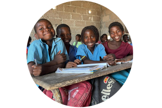 Circular image of children smiling in a classroom.